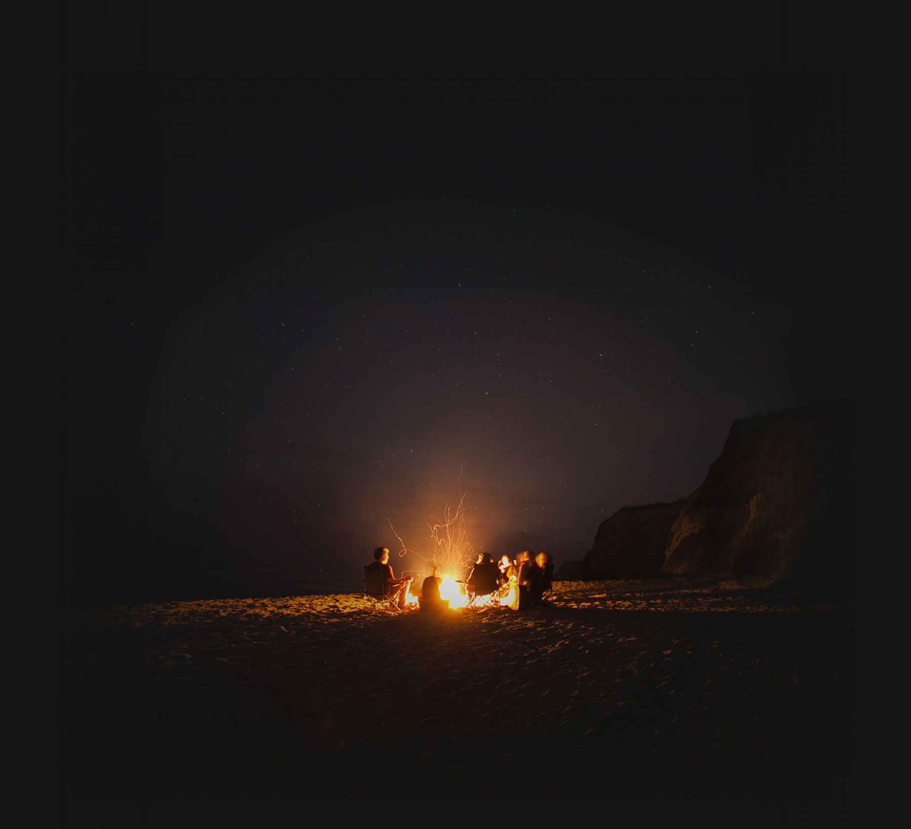 Sleepless team gathered around a fire on the beach